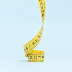 a measuring tape with the end cut in half on a light blue background that is almost empty