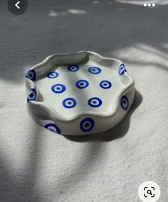 a blue and white bowl sitting on top of a bed next to a shadow cast tree