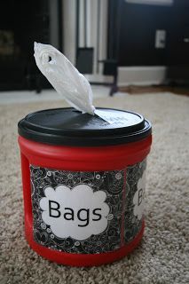 a red canister with a white owl on top sitting on the carpet in front of a black and white fireplace