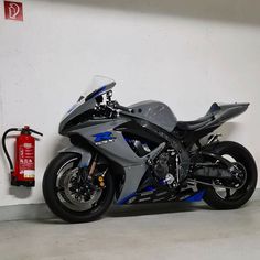 a silver motorcycle parked next to a red fire extinguisher in a garage