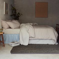 a bed sitting in a bedroom next to a wooden chair and table with a potted plant on top of it