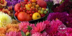 many different types of flowers and fruits are in the bowl on the table for sale