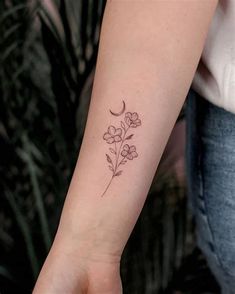 a woman's arm with a small flower tattoo on the left side of her wrist