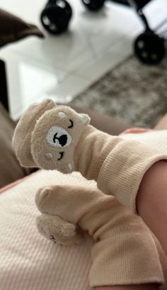 a small teddy bear is wrapped up in a pair of baby socks and sitting on someone's lap