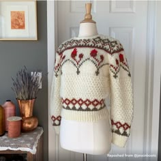 a sweater on a mannequin next to some vases and other items in front of a door