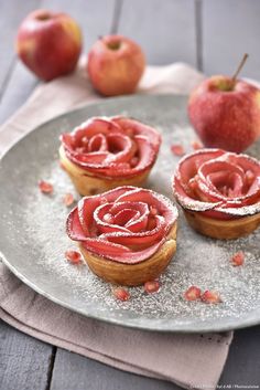 three pastries on a plate with apples in the background