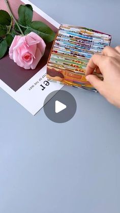 a person holding a pink rose in front of a card with the word love on it