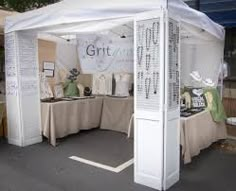 a white tent sitting on the side of a road next to tables covered in cloth