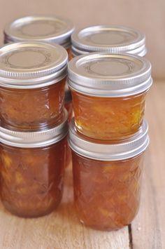 four jars filled with food sitting on top of a wooden table