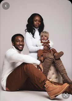 a man, woman and child sitting on the ground