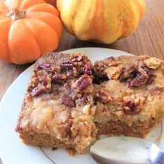 two pieces of cake on a plate with a spoon and pumpkins in the background