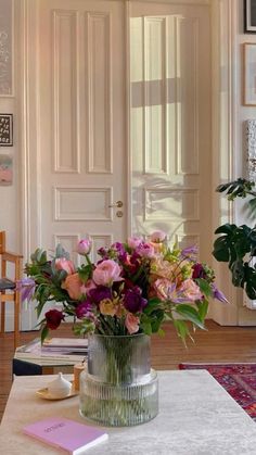 a vase filled with lots of flowers on top of a table next to a door