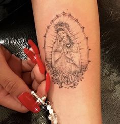 a woman's arm with a tattoo on it and an image of the virgin mary