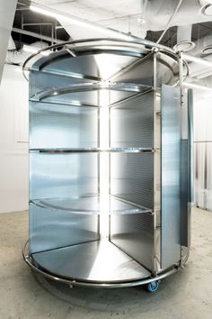 a large round metal object in the middle of an empty room with lots of shelves