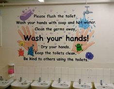 a bathroom with several urinals and handwash signs on the wall above them