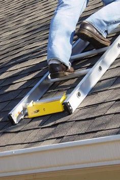 a man working on the roof of a house with a ladder attached to his shingles