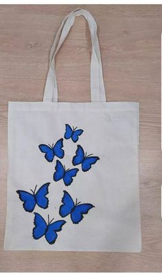 a white bag with blue butterflies on the front and bottom, sitting on a wooden floor