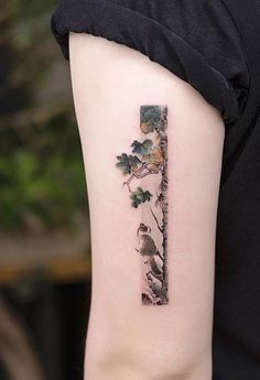 a person with a tattoo on their arm has a bird and tree in the shape of a letter