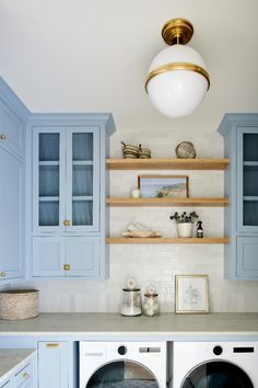 a washer and dryer in a room with blue cabinets on either side of the washer