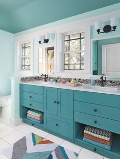 a bathroom with two sinks, blue cabinets and a rug on the floor in front of it