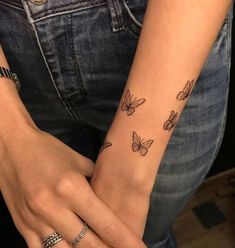 a woman's arm with butterfly tattoos on her left wrist and the other hand