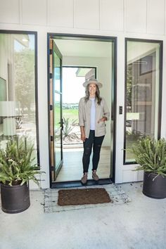 a woman standing in front of a door with her hands on her hips and wearing a hat