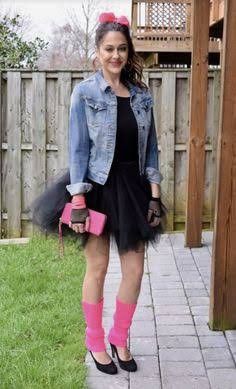 a woman in a black dress and pink socks is standing on the side walk near a wooden fence