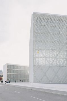 people are walking on the sidewalk in front of a building with white walls and windows