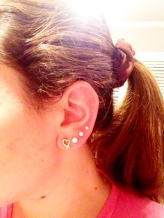 a close up of a person with ear piercings on their ears and wearing a pink shirt