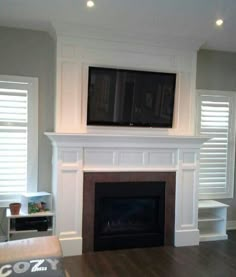 an empty living room with a fireplace and tv above the mantel in front of it