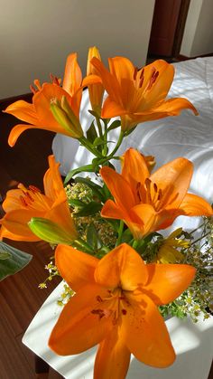 an arrangement of orange flowers in a vase on a table