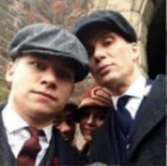 two men in suits and ties are posing for a photo with one man wearing a hat