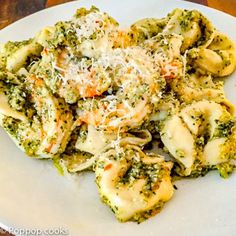 a white plate topped with pasta and broccoli covered in cheese on top of it