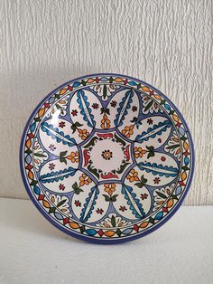 a colorful plate sitting on top of a white counter next to a wall with peeling paint