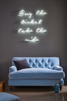 a blue couch sitting in front of a wall with neon lights on it's sides