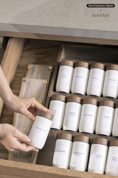 two hands reaching for coffee mugs in a wooden box with labels on the bottom