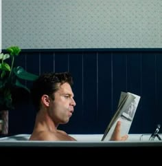 a man sitting in a bathtub reading a book