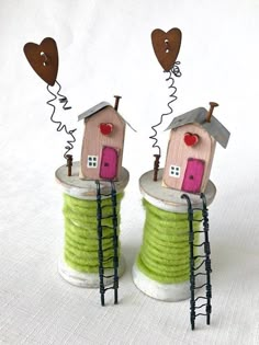 there are two small houses on top of some spools with hearts flying out of them