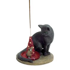 a cat figurine sitting on top of a table next to a red hat