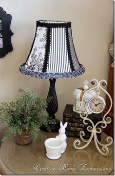 a lamp sitting on top of a table next to a clock and potted plant