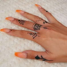 a woman's hand with tattoos on it and an orange nail polish vare