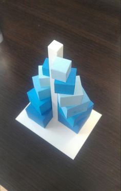 a paper sculpture is sitting on top of a wooden table and it appears to be made out of different colored blocks