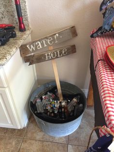 a bucket filled with bottles next to a sign that says water hole