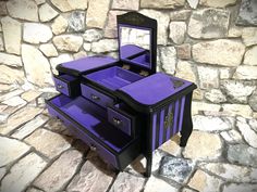 a purple and black dresser sitting on top of a stone floor