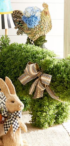 a stuffed rabbit sitting on top of a grass covered ground next to a lamp and potted plant