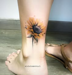 a woman's foot with a sunflower tattoo on it