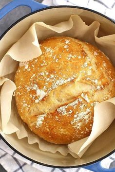 a baked bread in a blue pot on a white and gray tablecloth with a napkin