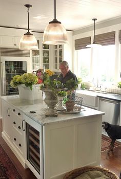 a man standing in a kitchen next to a counter with flowers on it and an oven