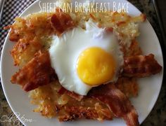 an egg and hash browns on a white plate with a black pan in the background