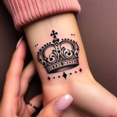 a woman's wrist tattoo with a crown and stars on her left hand,